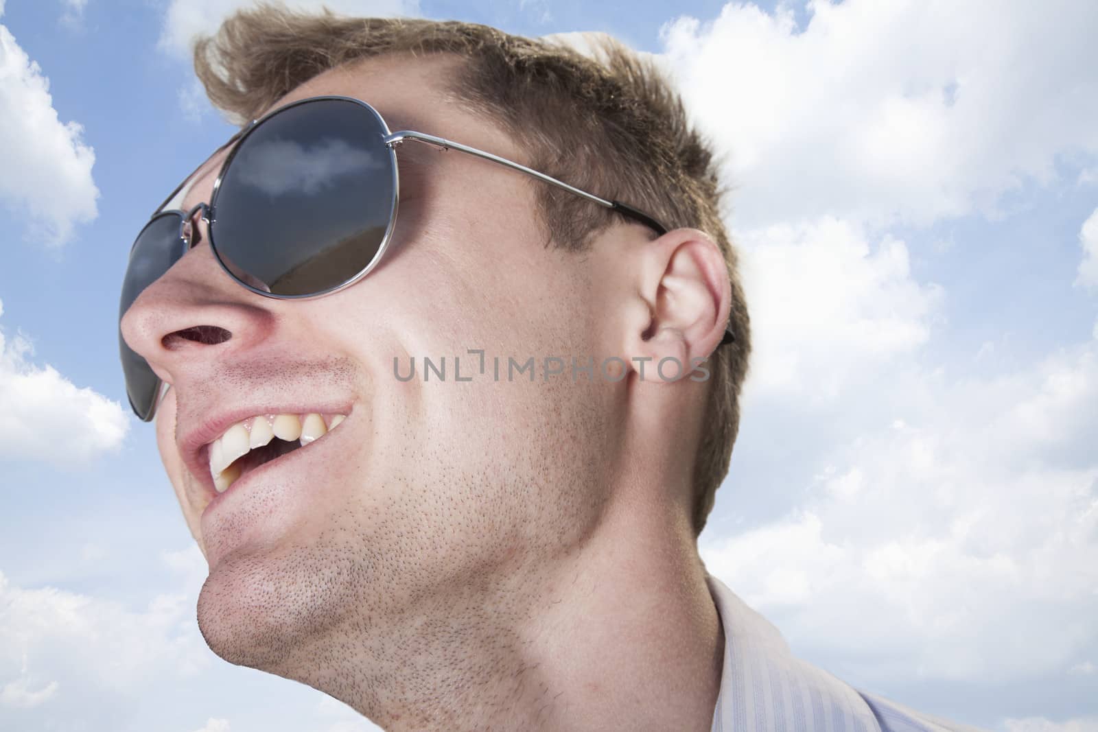 Portrait of young businessman in sunglasses smiling, close-up on face