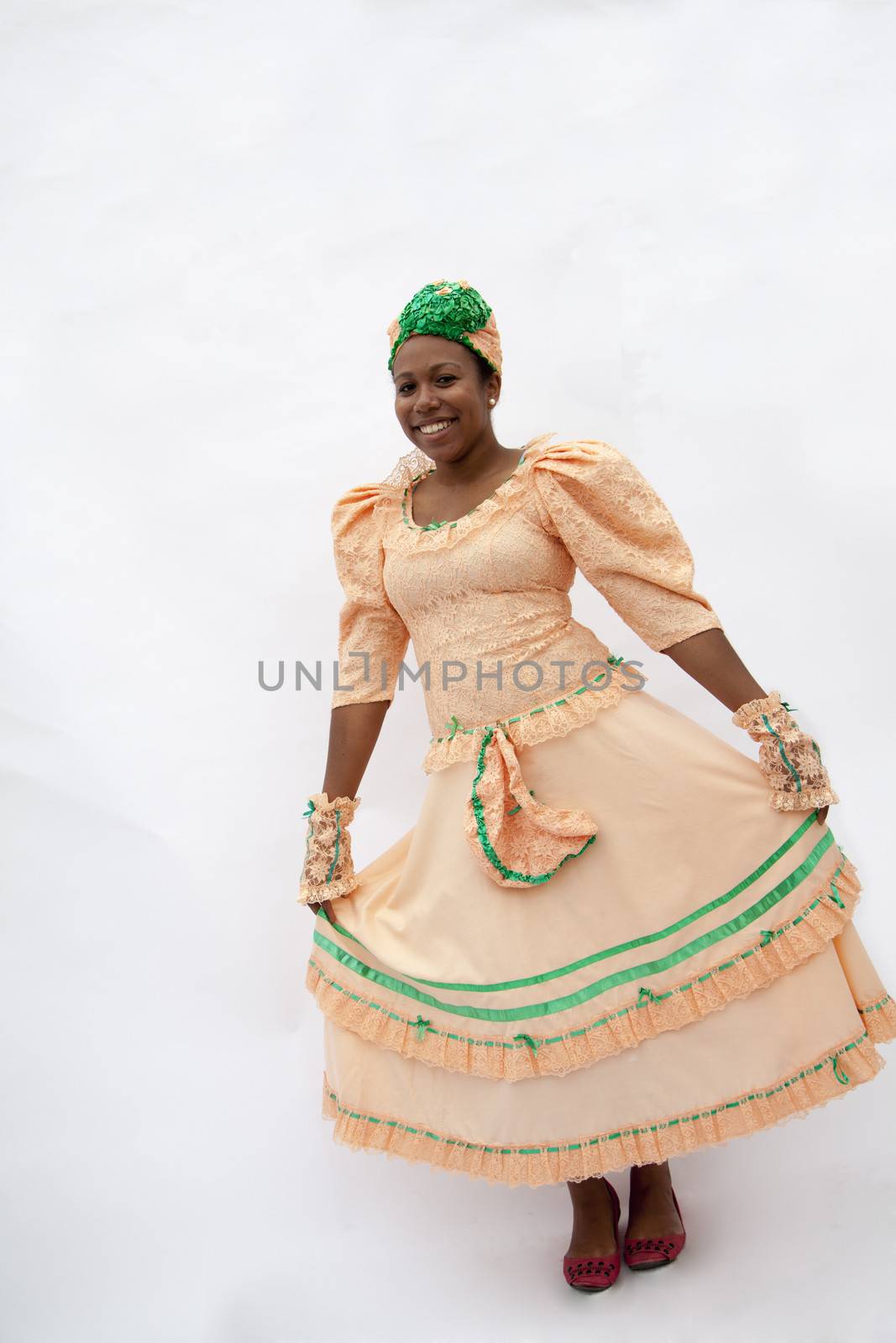 Portrait of young smiling woman holding her skirt in traditional clothing from the Caribbean, studio shot