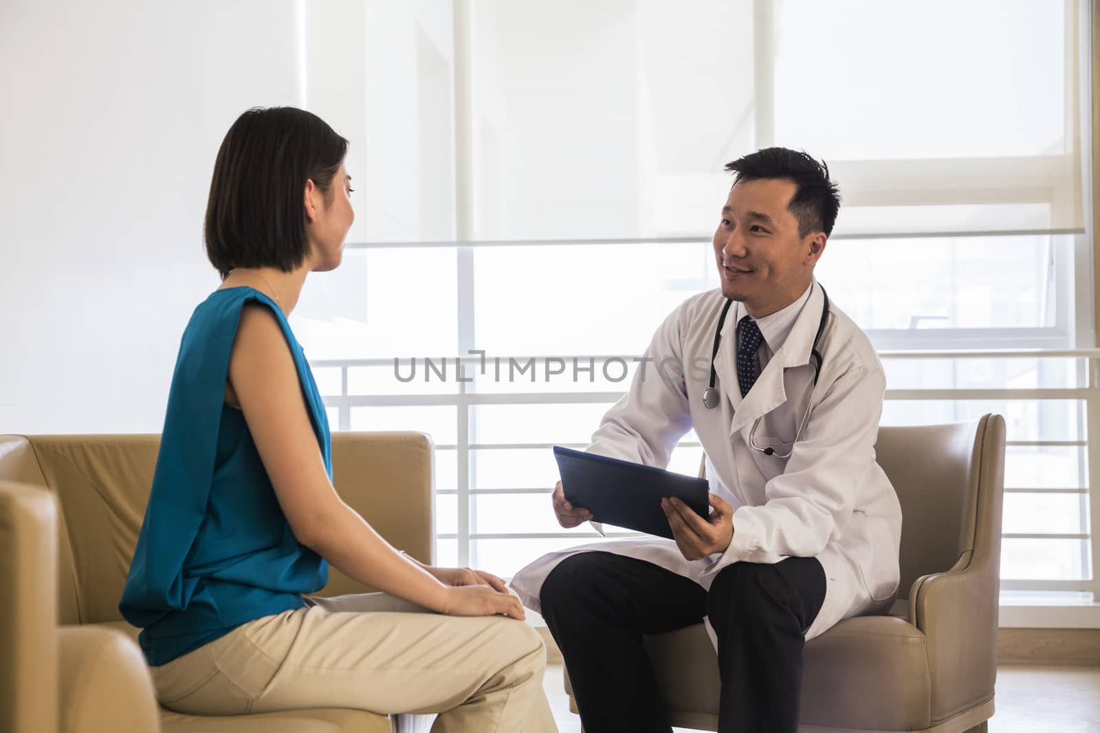 Doctor sitting down and consulting patient in the hospital by XiXinXing