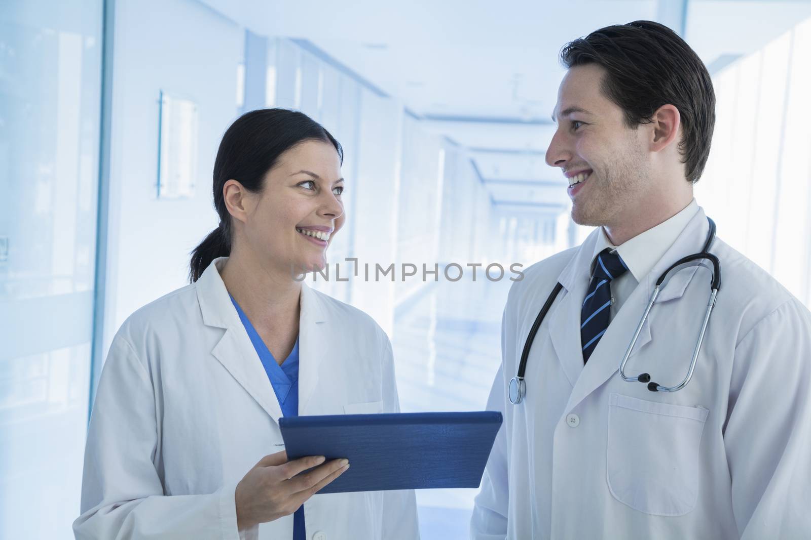 Two smiling doctors looking and holding a medical record in the hospital