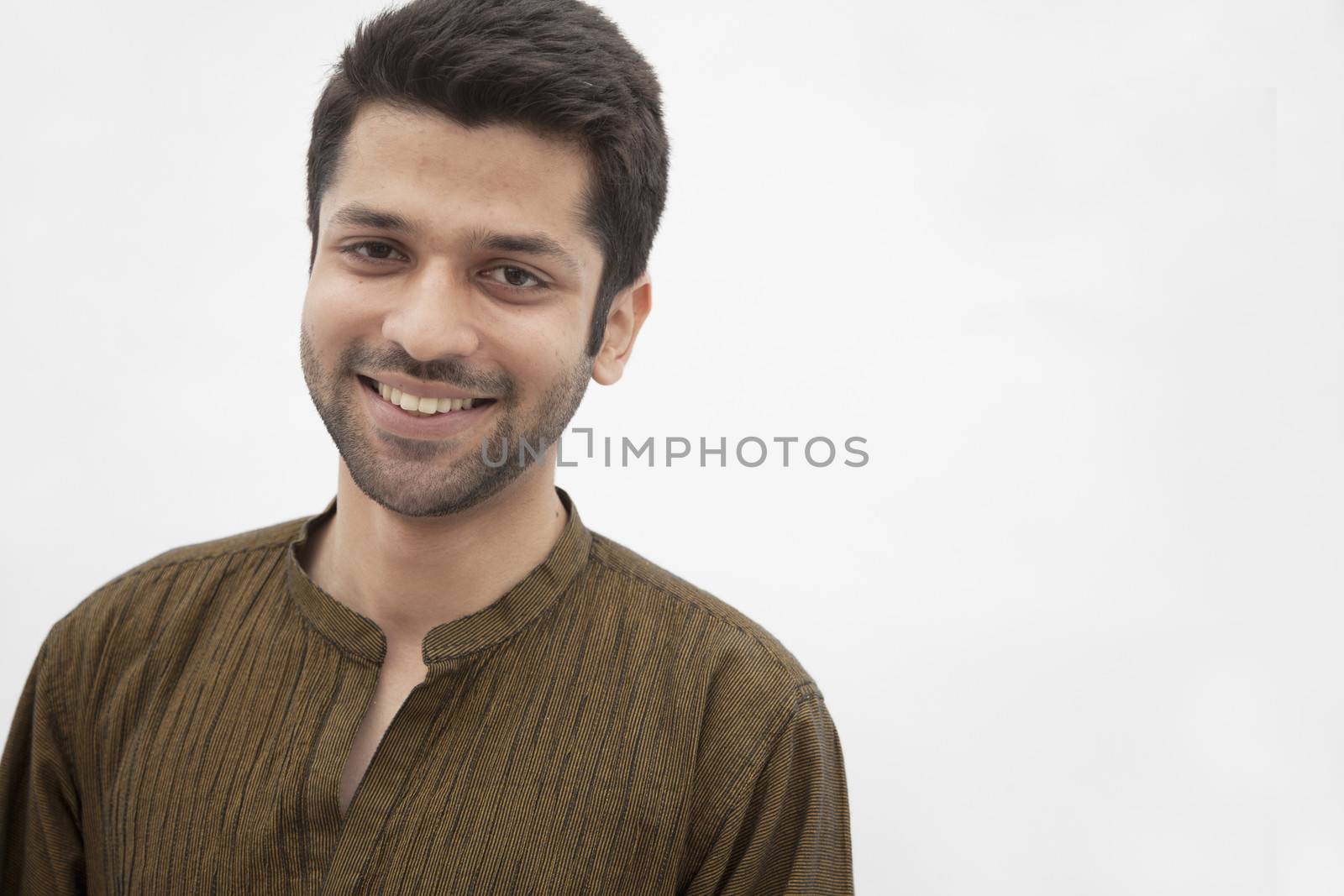 Portrait of smiling young man wearing traditional clothing from Pakistan, studio shot by XiXinXing