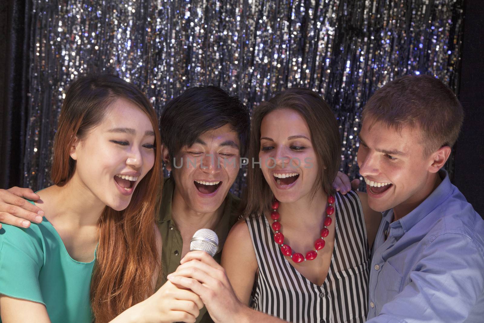 Four friends singing together at karaoke