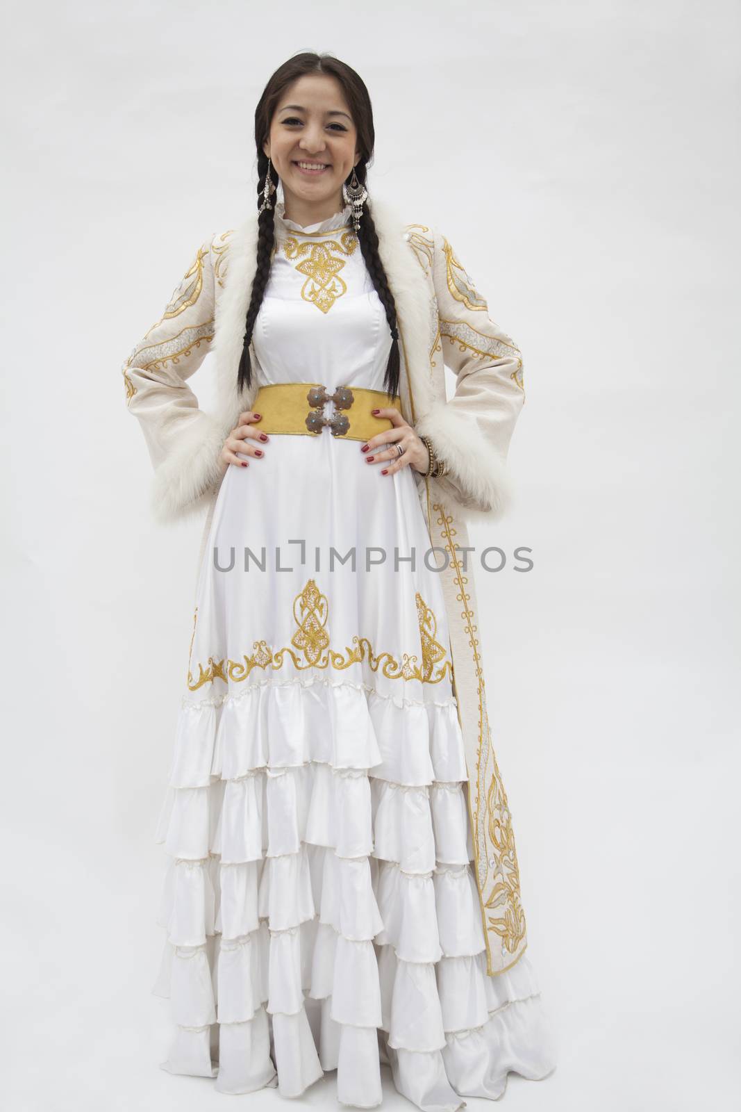 Portrait of young smiling woman with braids in traditional clothing from Kazakhstan, studio shot