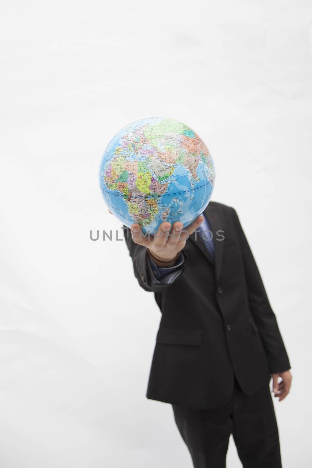 Businessman in a suit holding up a globe in front of his face, obscured face, studio shot by XiXinXing