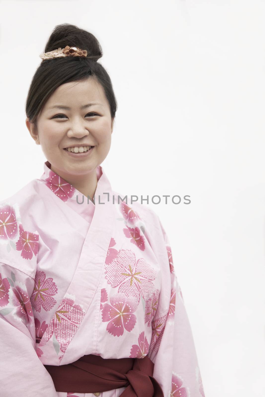 Portrait of young smiling woman in a pink Japanese kimono, studio shot