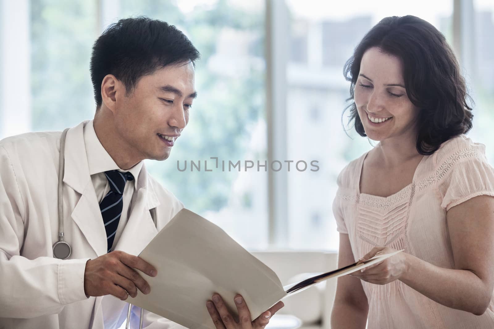 Doctor and patient sitting down and discussing medical record in the hospital by XiXinXing