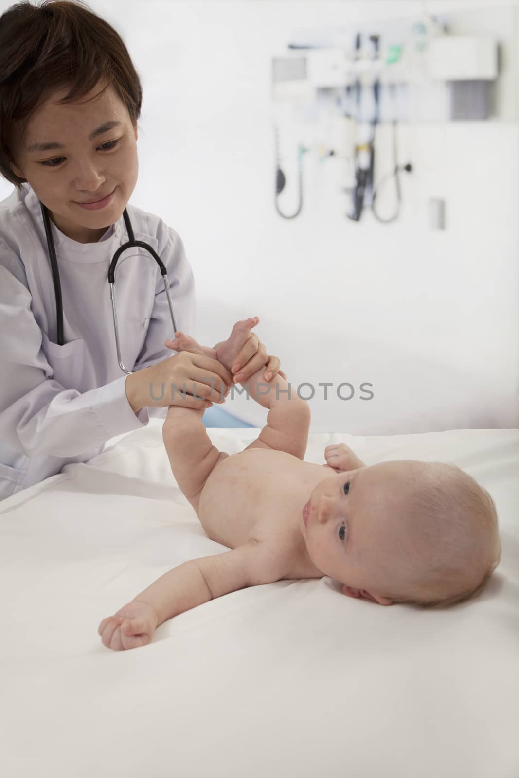 Smiling doctor examining a baby in the doctors office by XiXinXing