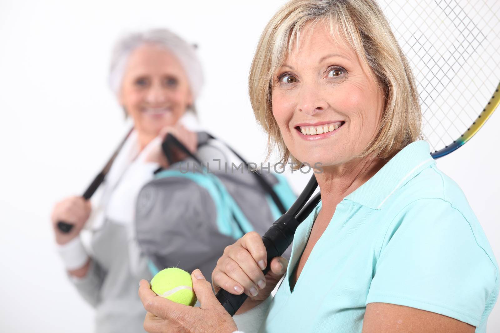 Older women playing tennis by phovoir