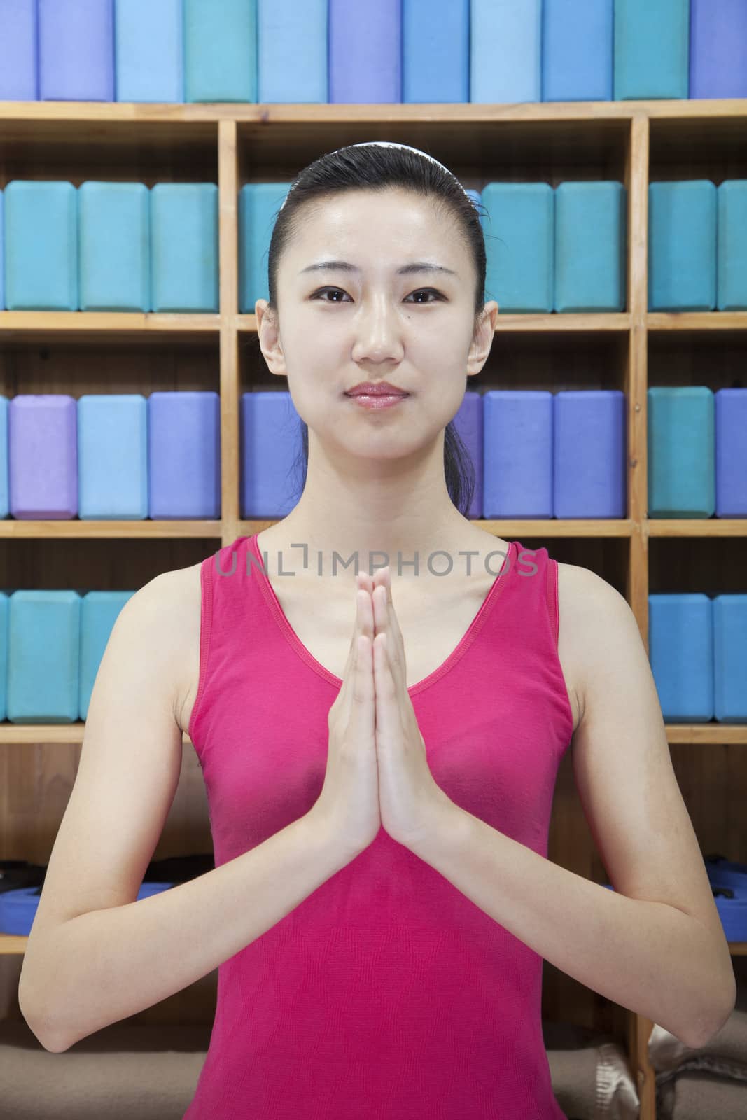 Portrait of young women doing yoga with hands clasped together, looking at camera