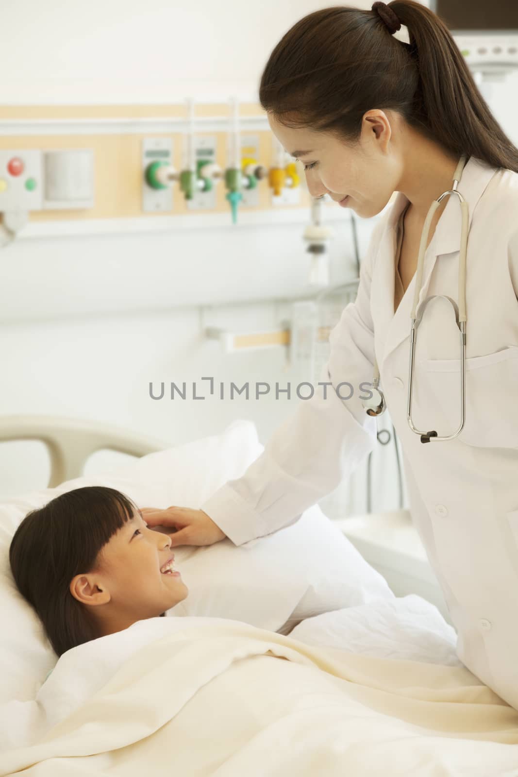 Female doctor talking to girl patient lying down on a hospital bed