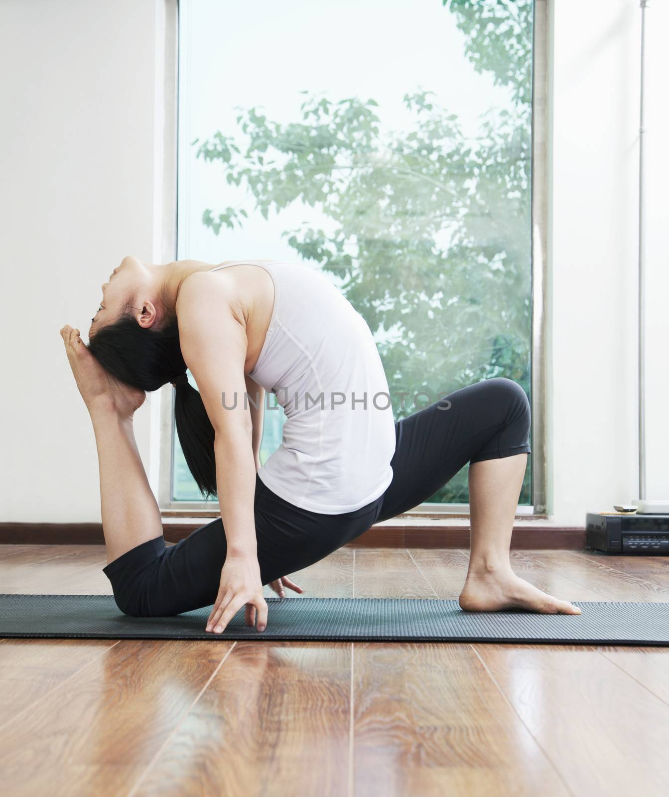 Woman bent over backwards in a yoga position in a yoga studio, side view