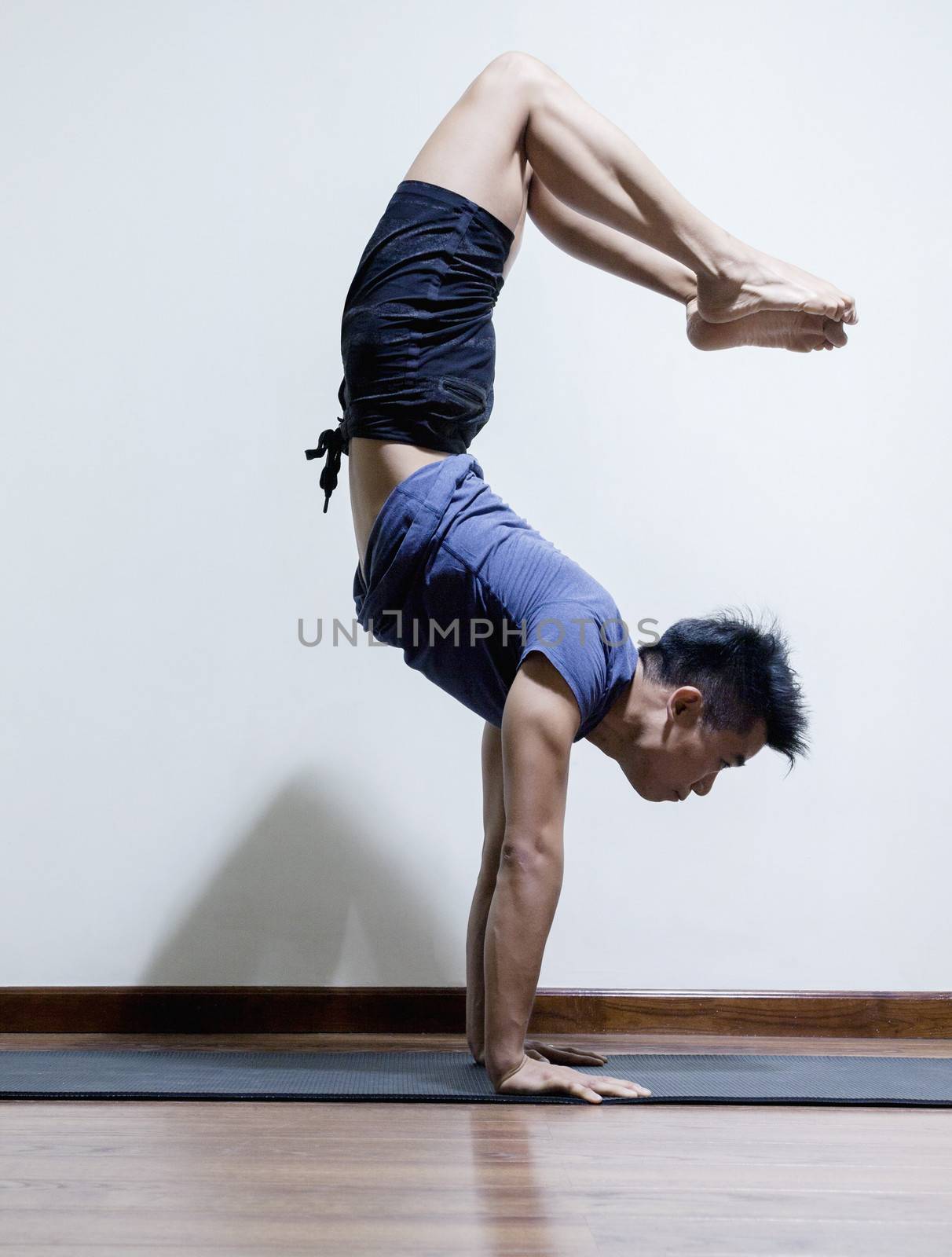 Upside down man doing yoga in a yoga studio, side view