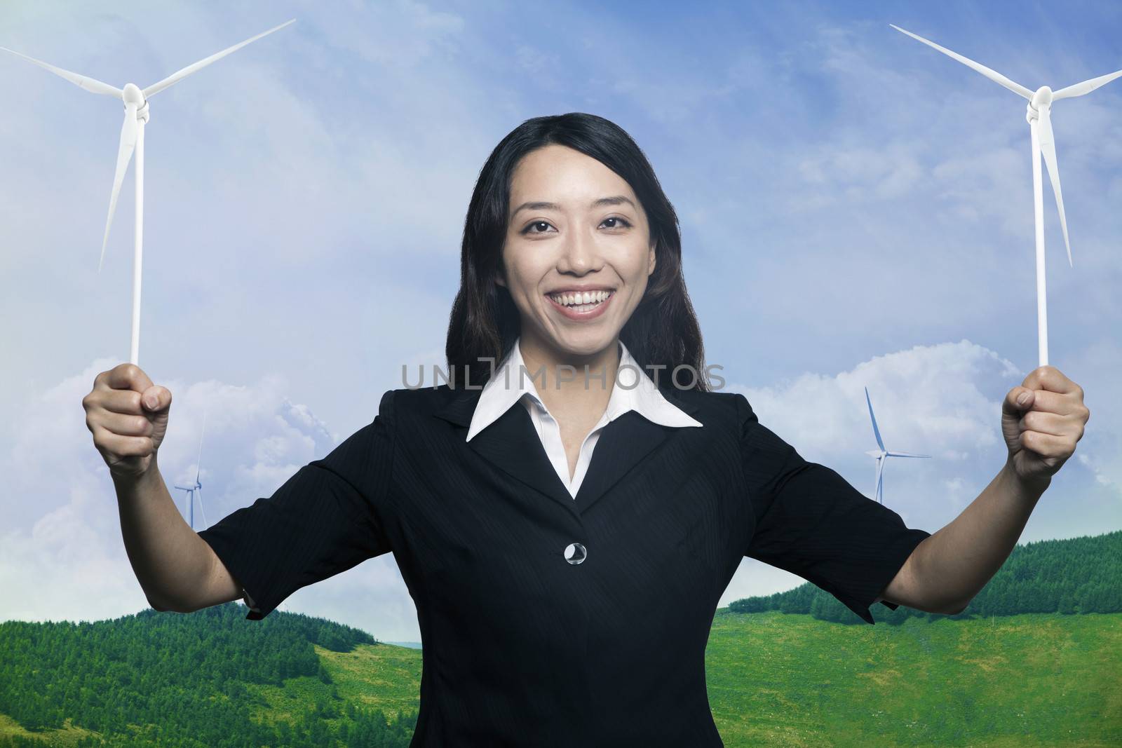 Young smiling woman holding to wind turbines and looking at camera