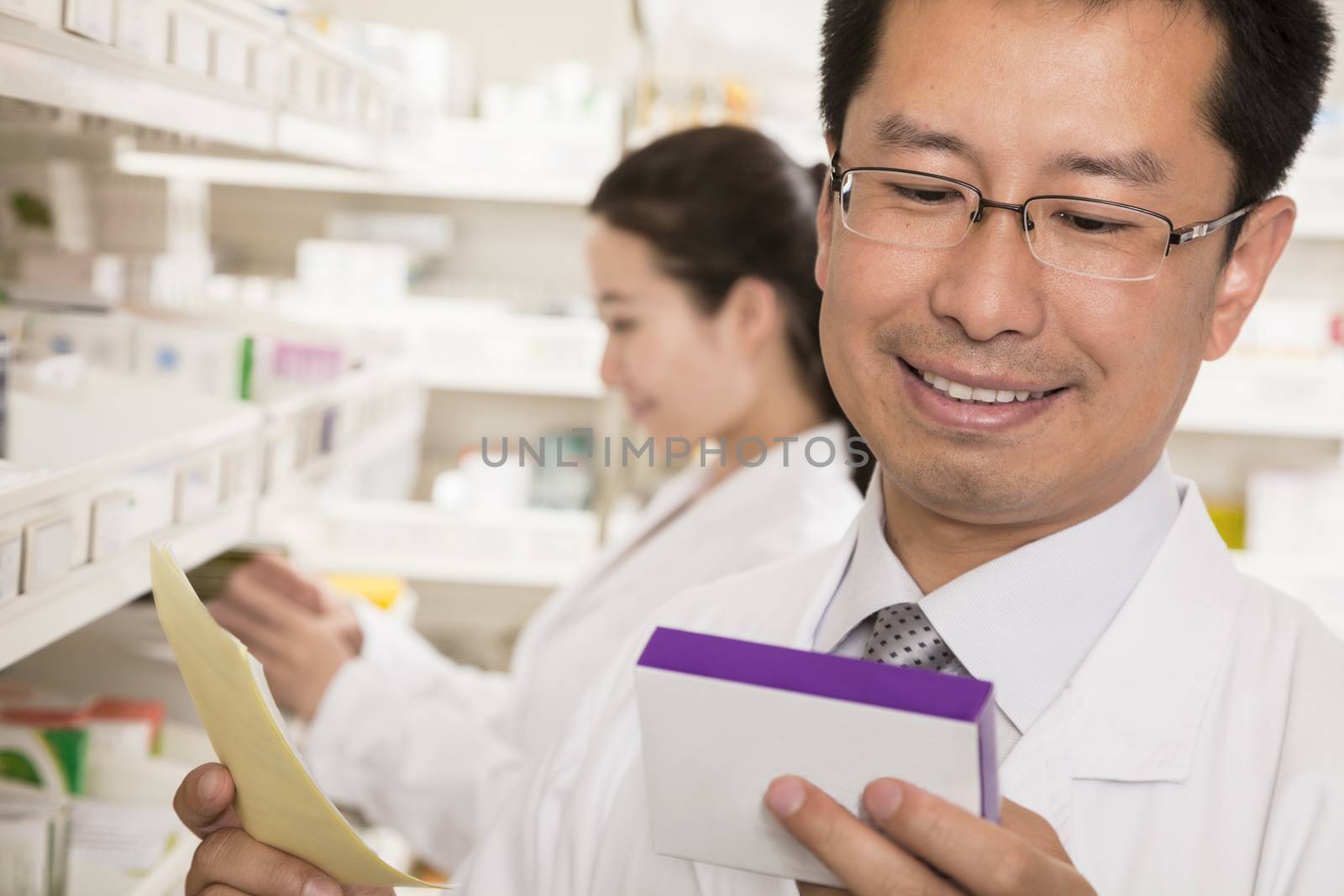 Pharmacist looking down and examining prescription medication in a pharmacy