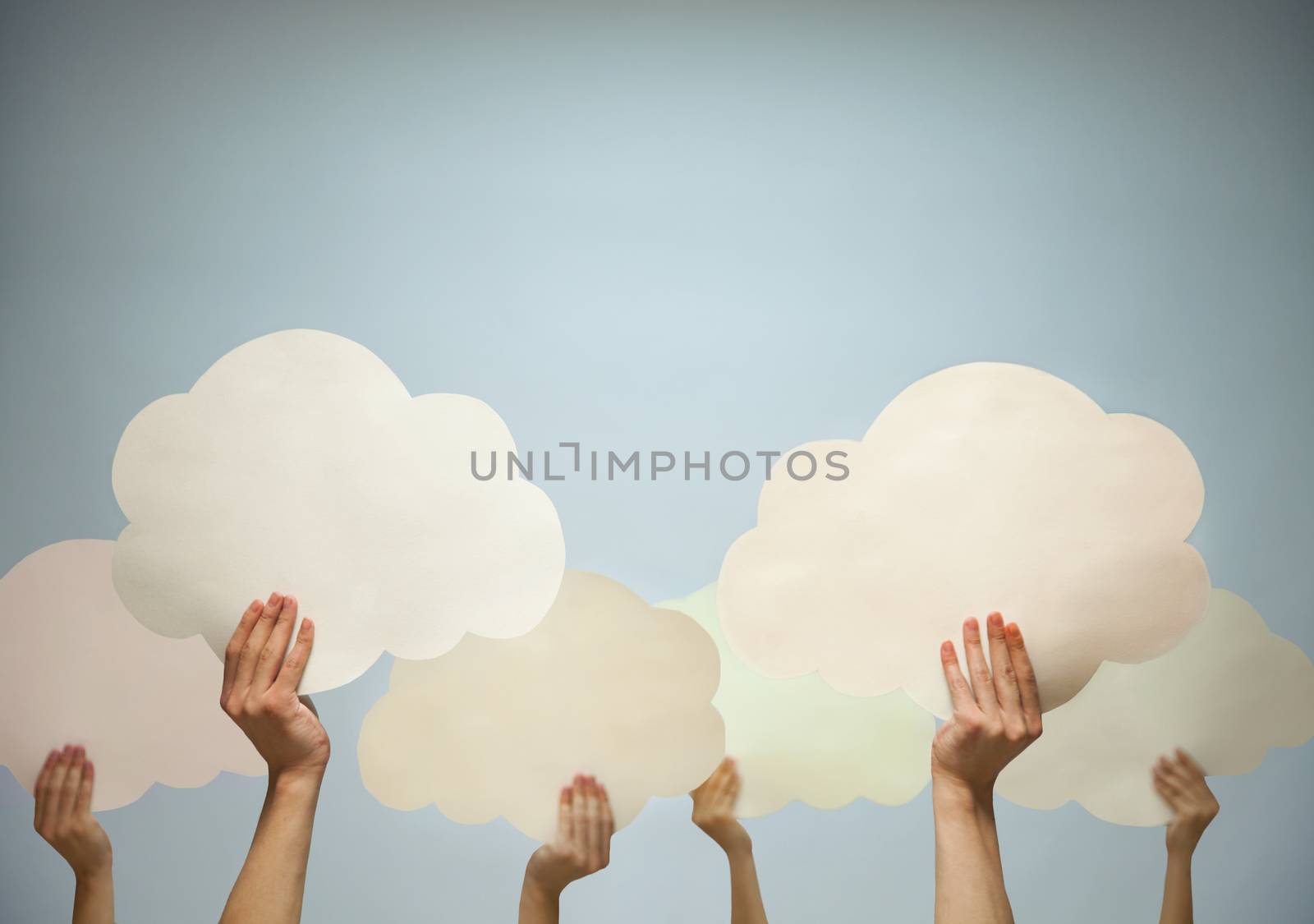 Multiple hands holding cut out paper clouds against a blue background, studio shot