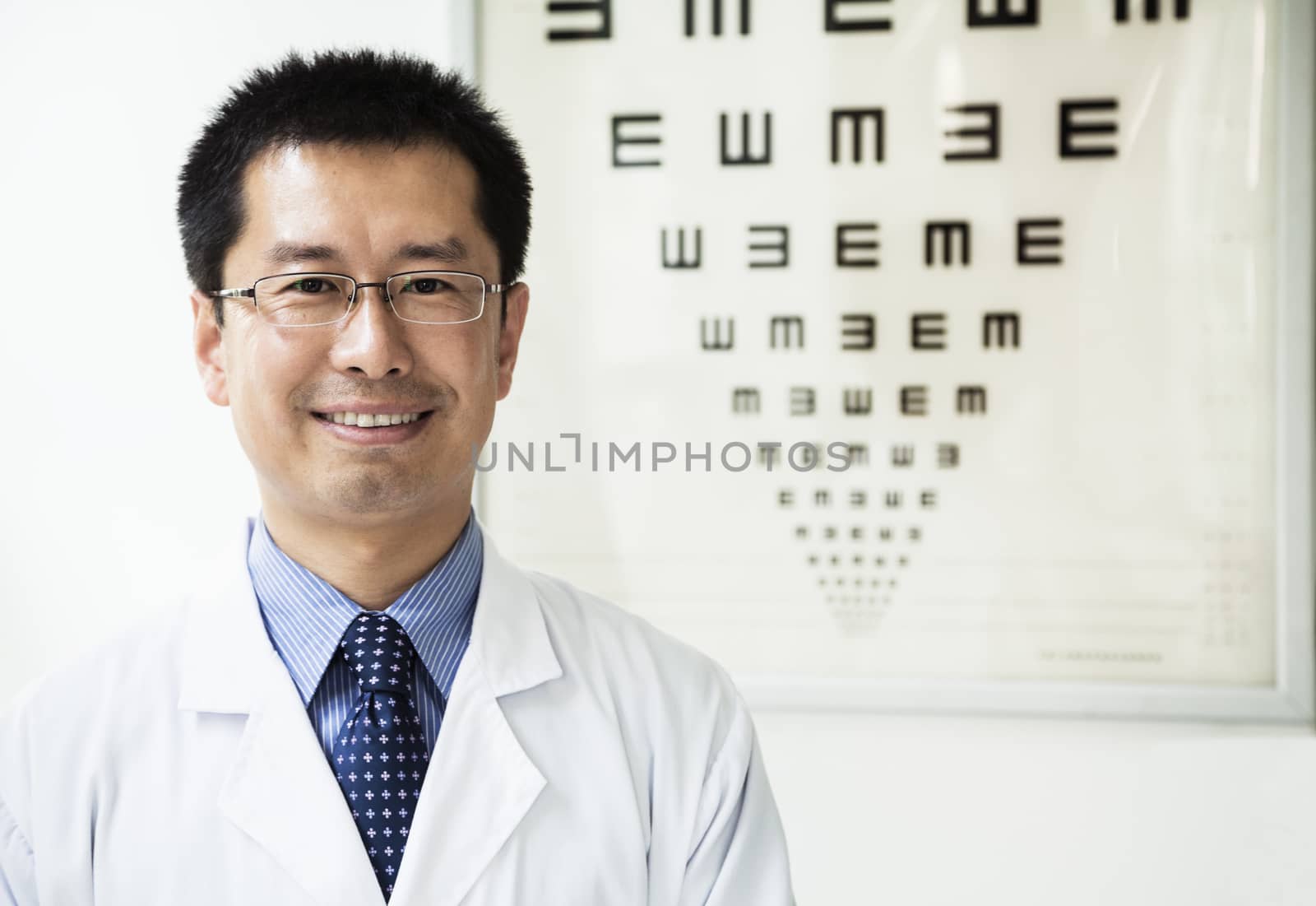 Portrait of smiling optometrist with an eye chart in the background