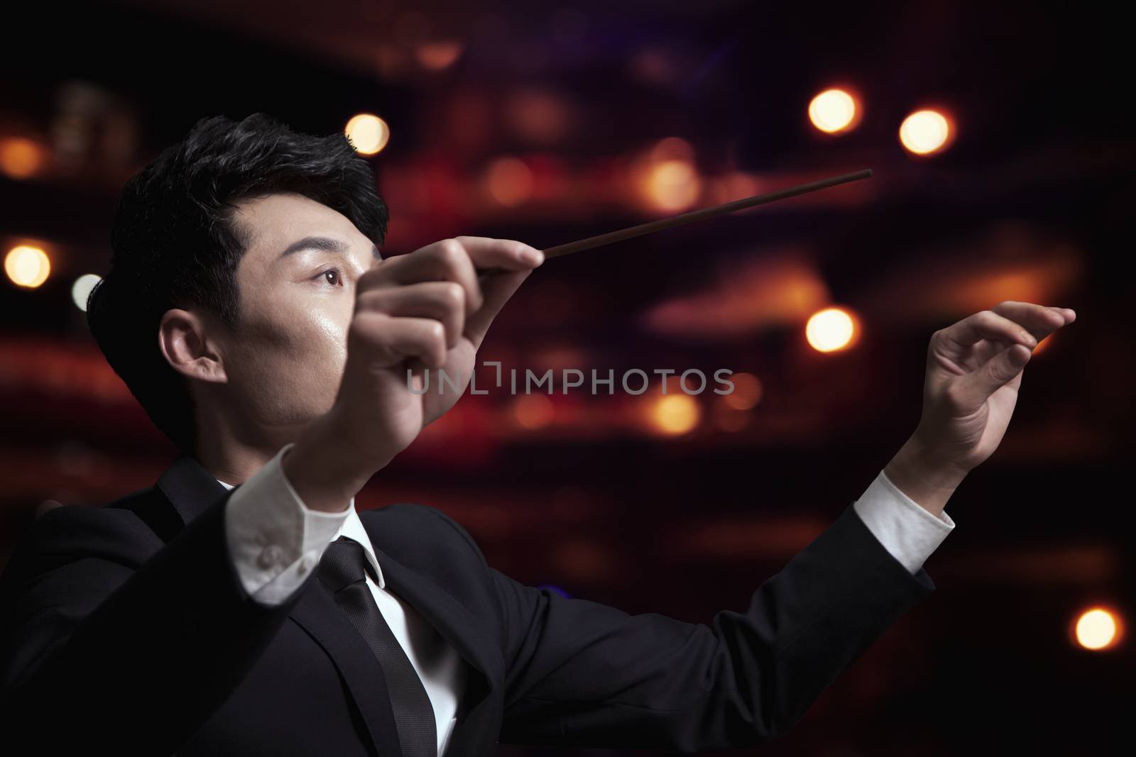 Young conductor with baton raised at a performance  by XiXinXing