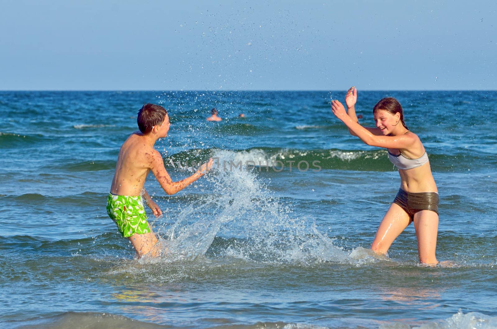 children splashing at the sea in summer day