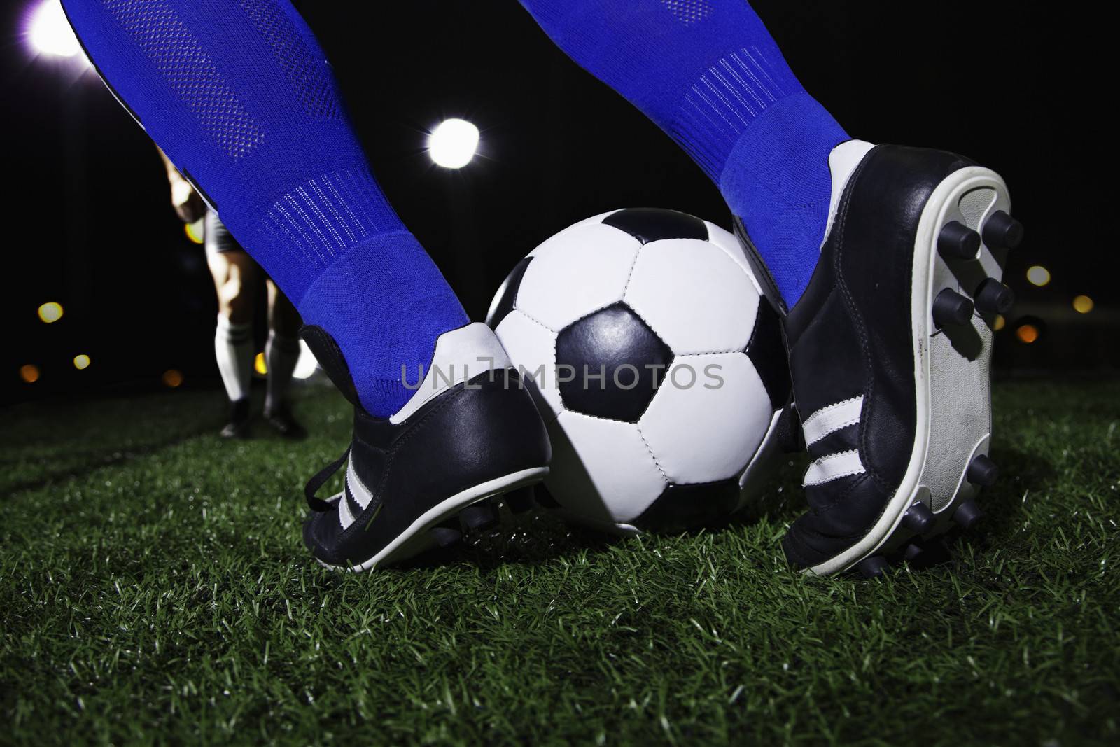 Close up of feet kicking the soccer ball, night time in the stadium