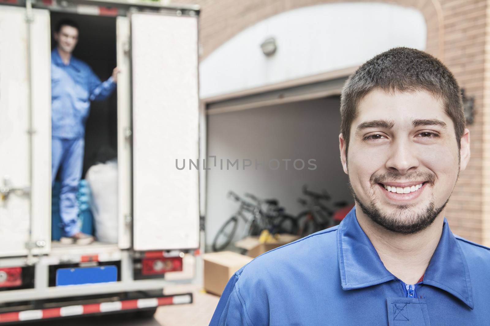 Portrait of smiling mover with moving truck in the background by XiXinXing