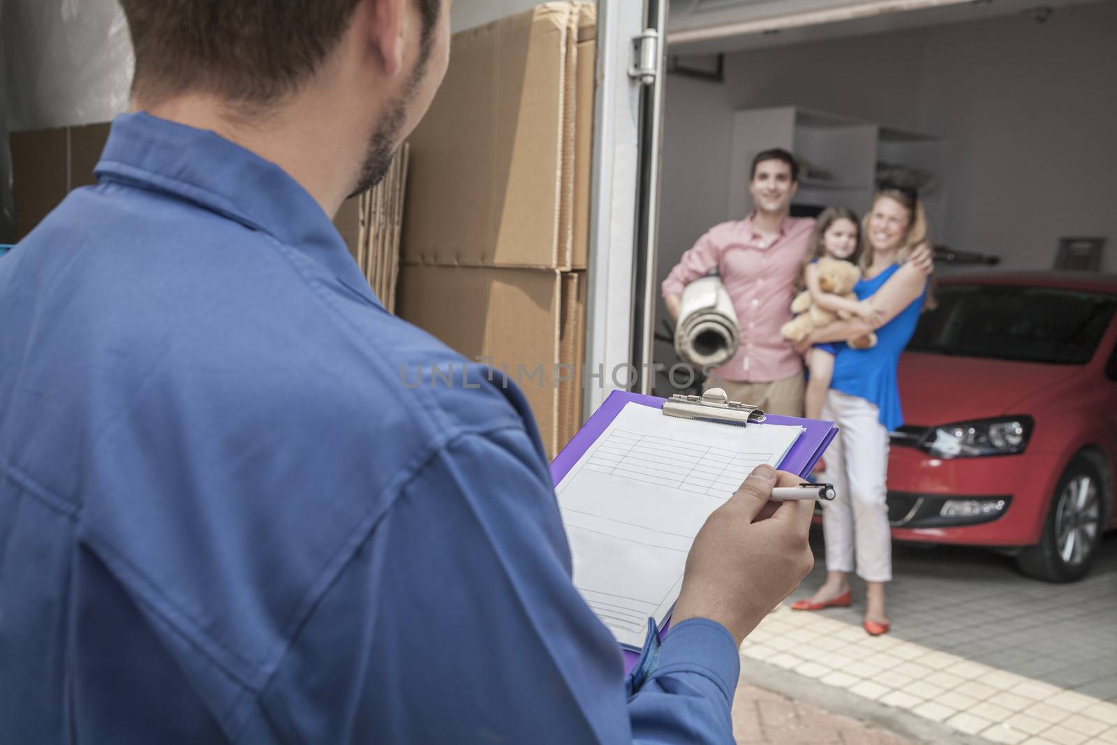 Mover holding clipboard and invoice, family in the background by XiXinXing