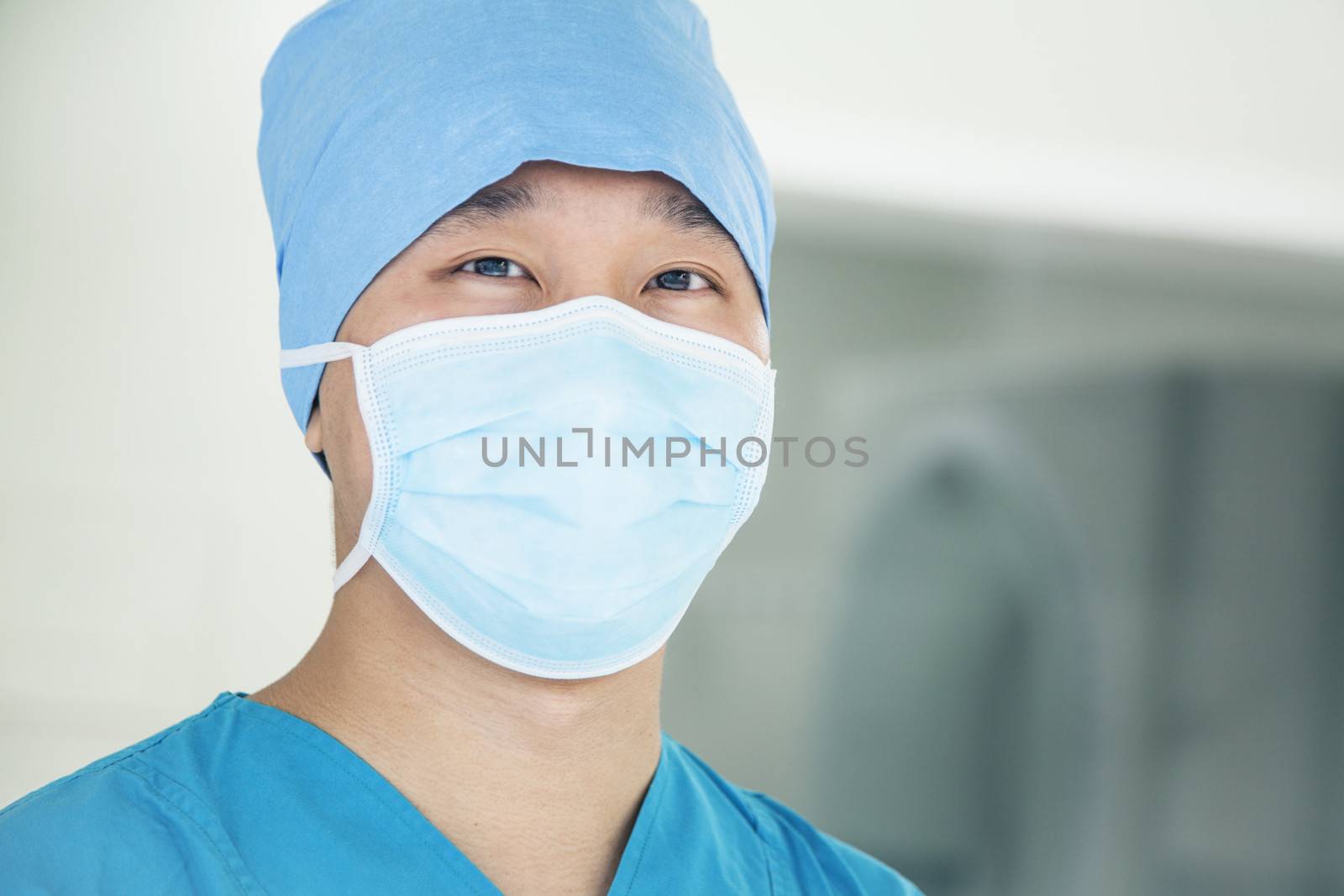 Portrait of young surgeon wearing surgical mask in the operating room, close- up by XiXinXing