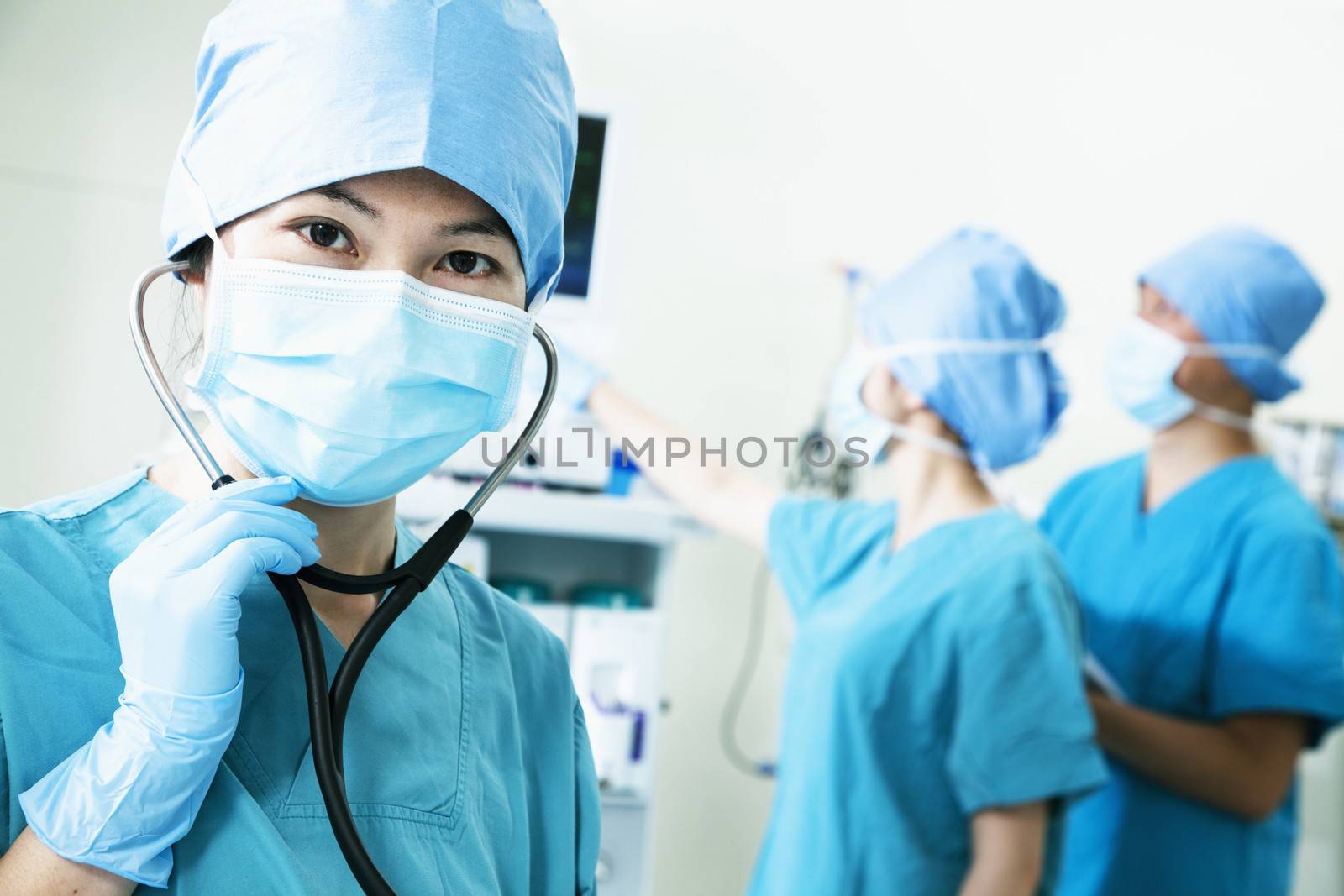 Team of surgeons in the operating room, female surgeon holding stethoscope and looking at camera