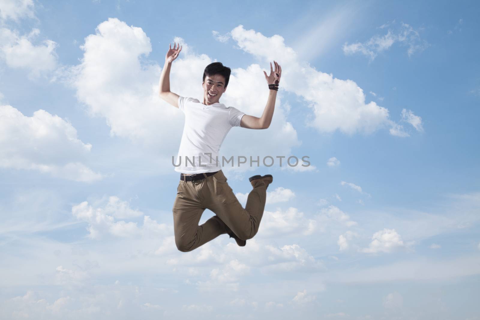 Young smiling man jumping in mid-air, sky and cloud background by XiXinXing