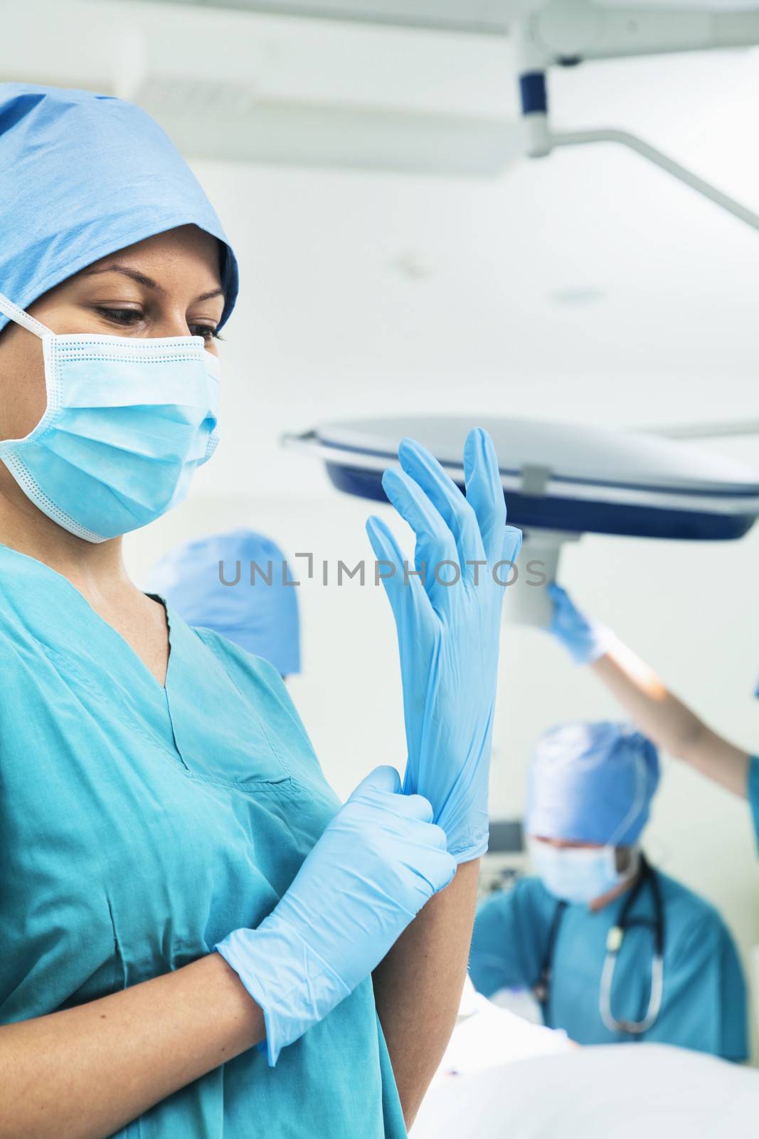 Female surgeon putting on gloves in the operating room, getting prepared