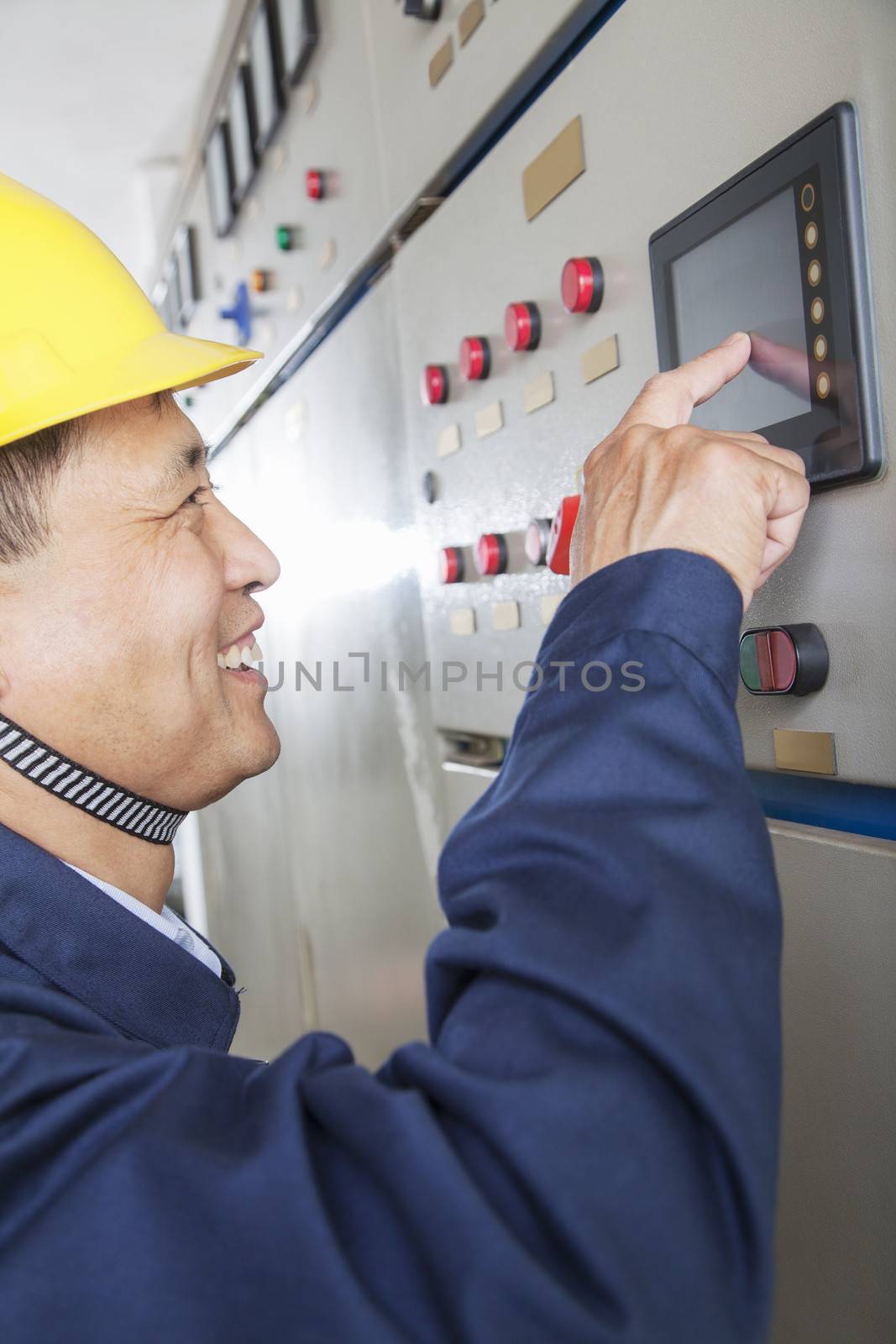 Smiling worker checking controls in a gas plant, Beijing, China by XiXinXing