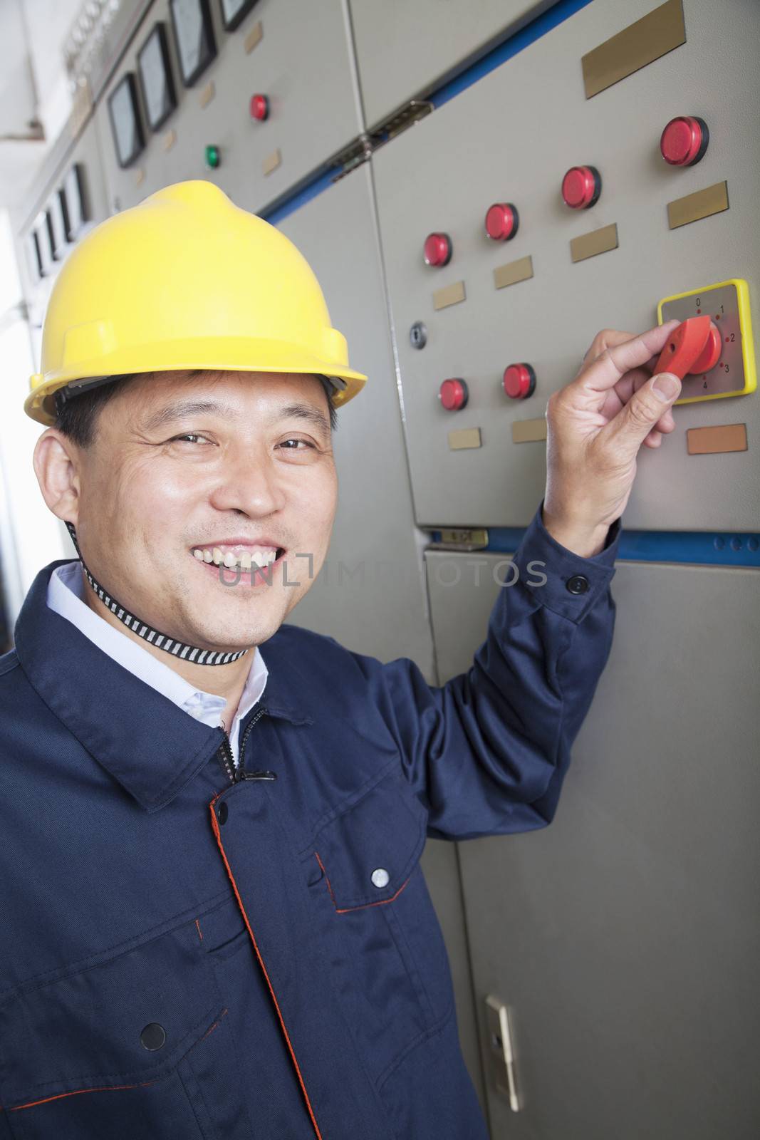 Smiling worker checking controls in a gas plant, Beijing, China, looking at camera, portrait