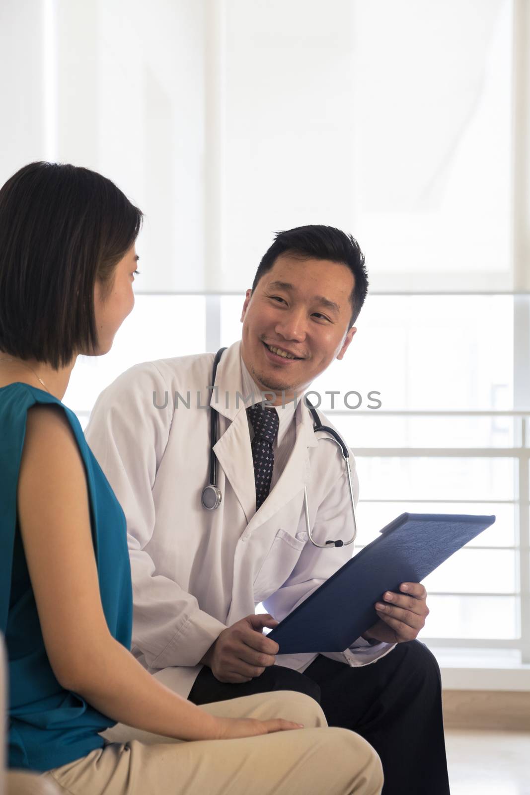 Smiling doctor sitting down and consulting patient in the hospital