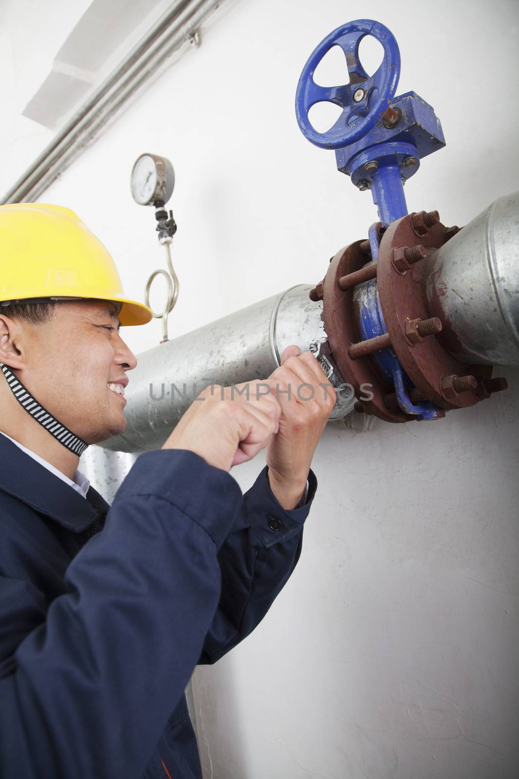 Smiling worker checking the oil pipeline equipment in a gas plant, Beijing, China