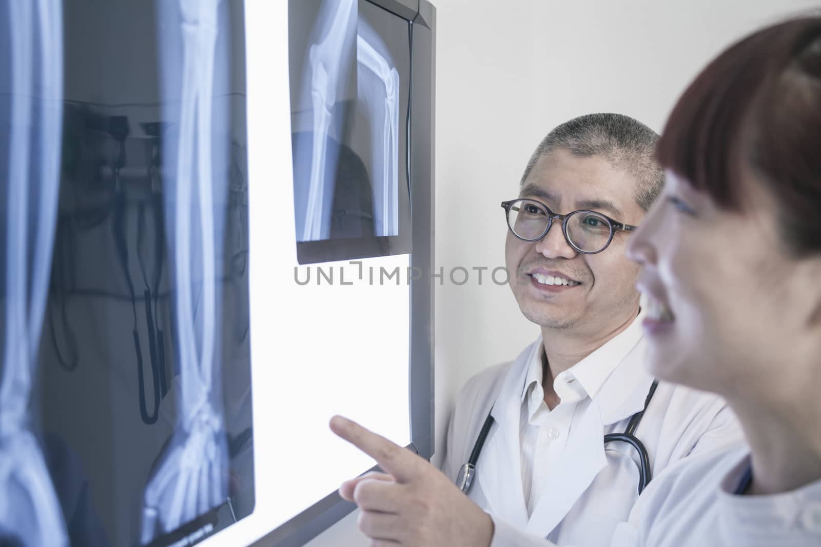 Two smiling doctors looking at x-rays of human bones, pointing