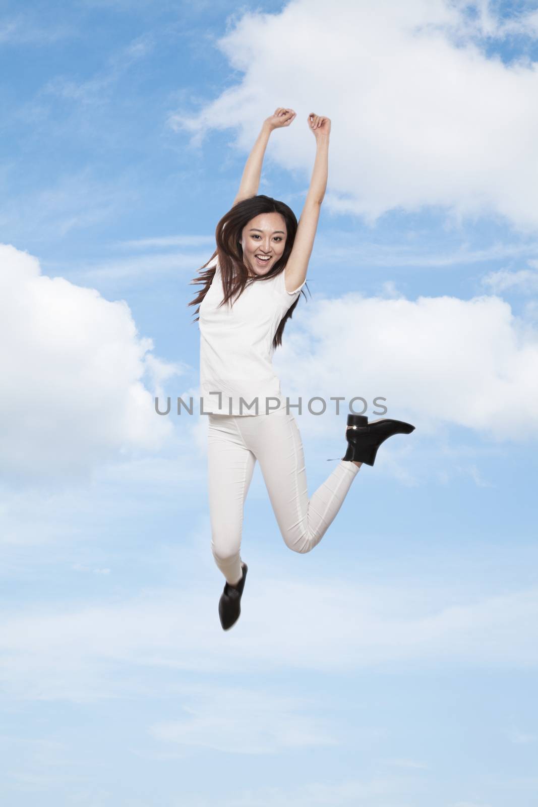 Young smiling woman jumping in mid-air, sky and cloud background by XiXinXing