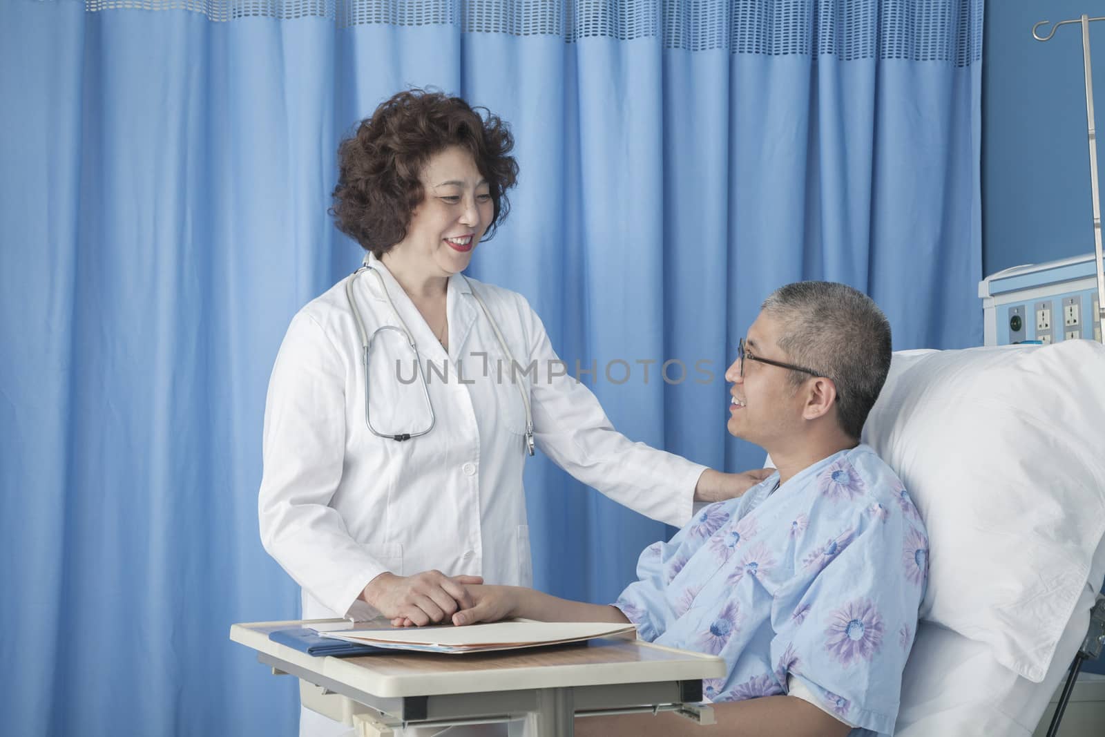 Smiling doctor checking up on a patient lying down in a hospital bed by XiXinXing