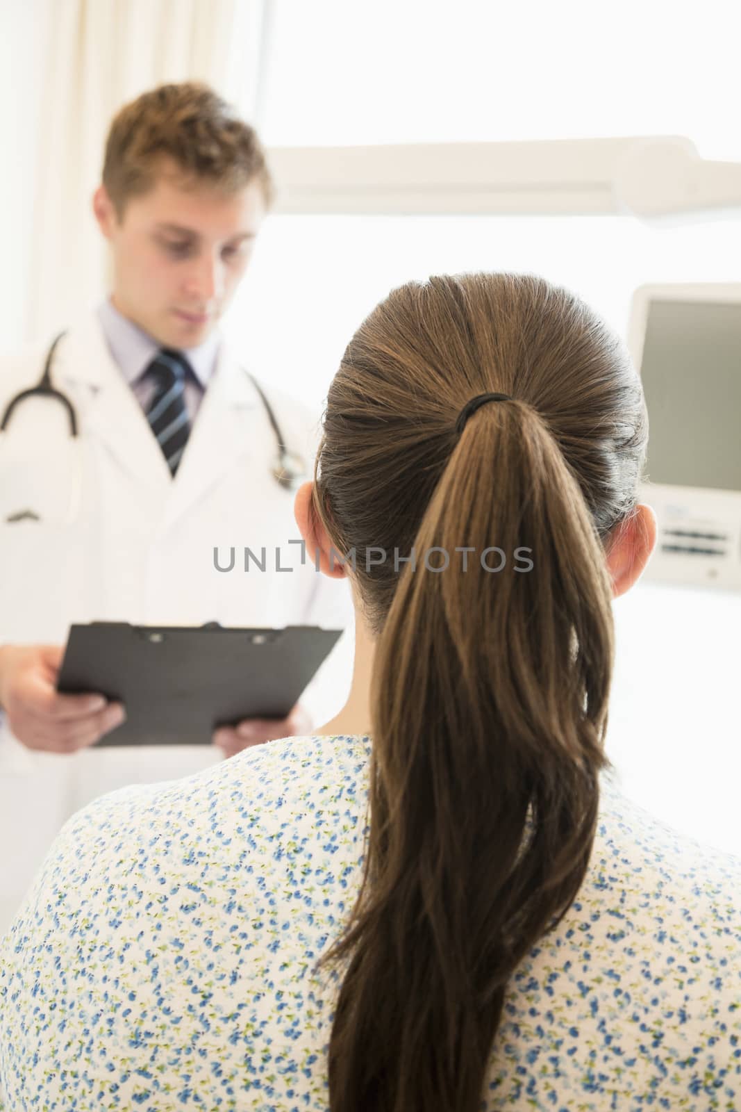Doctor discussing medical chart with a patient sitting on a hospital bed 