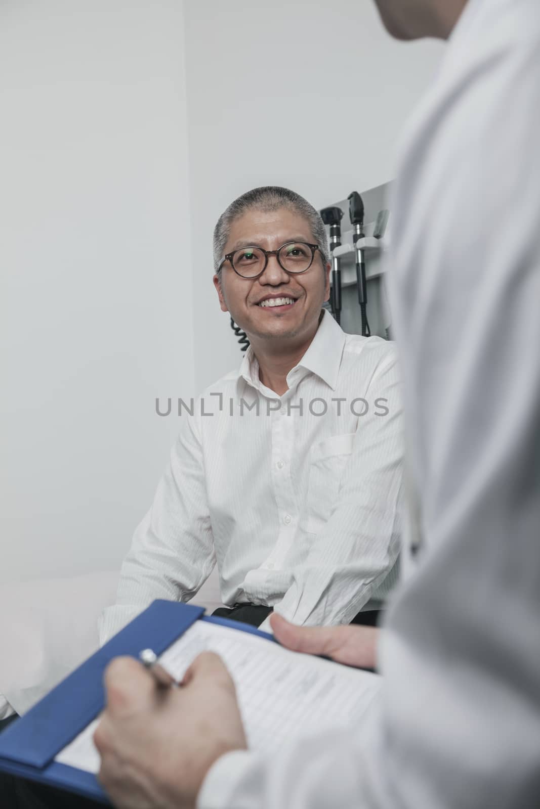 Doctor writing on medical chart with a smiling patient