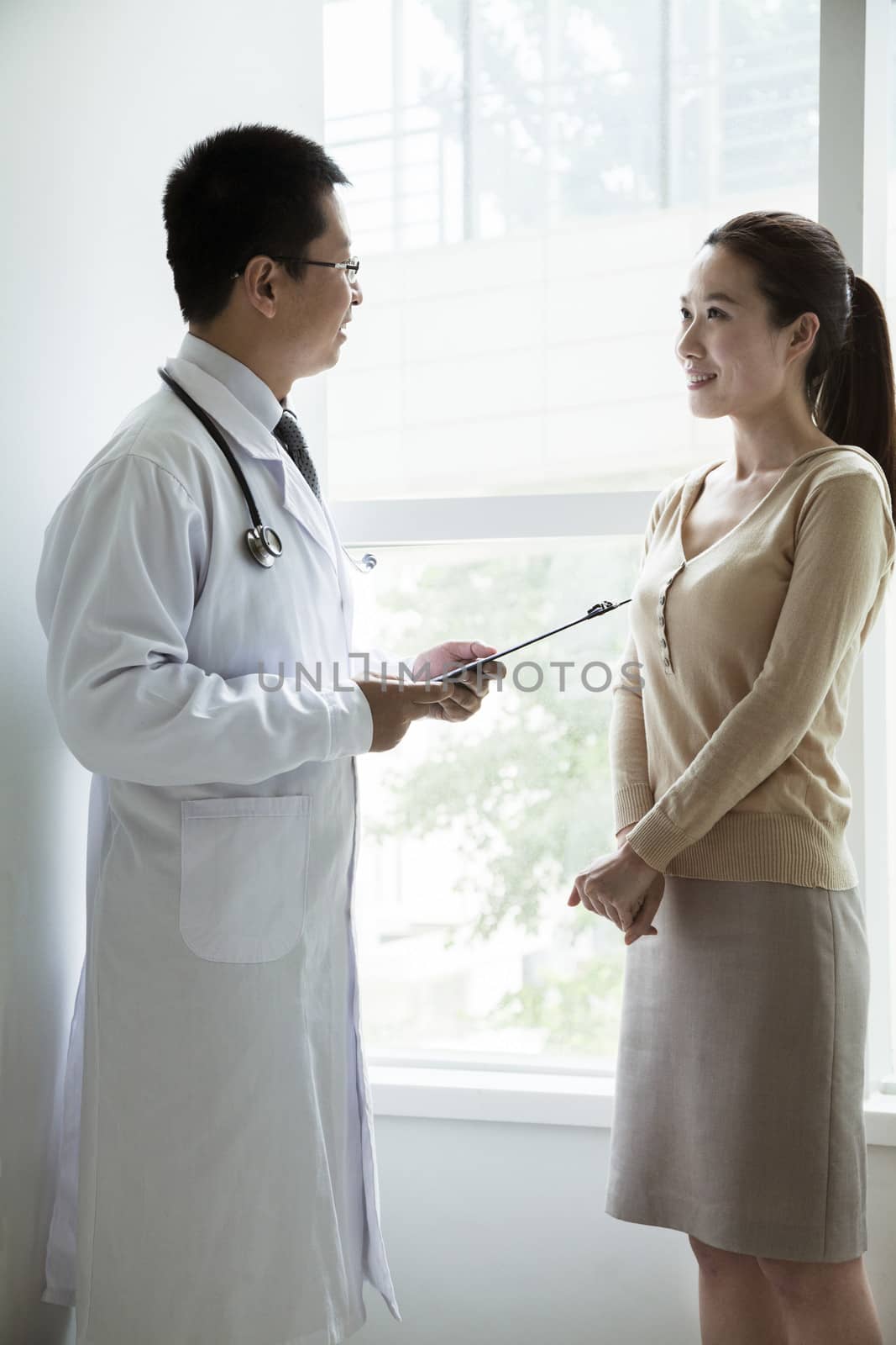 Doctor holding medical charts and discussing with a female patient in the hospital