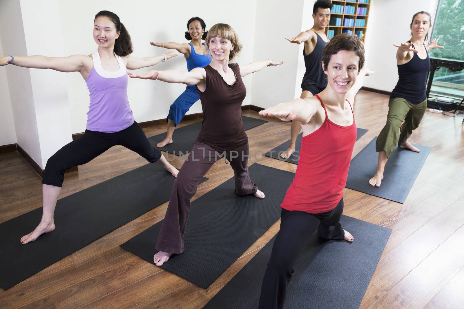 Group of people with arms outstretched doing yoga during a yoga class