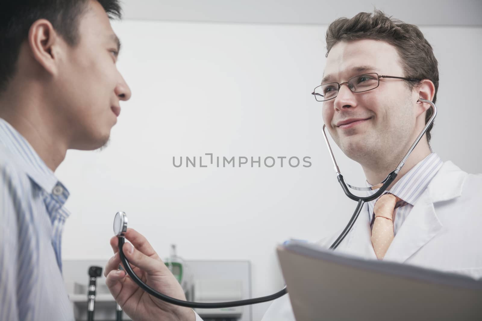 Smiling doctor checking heartbeat of a patient with a stethoscope