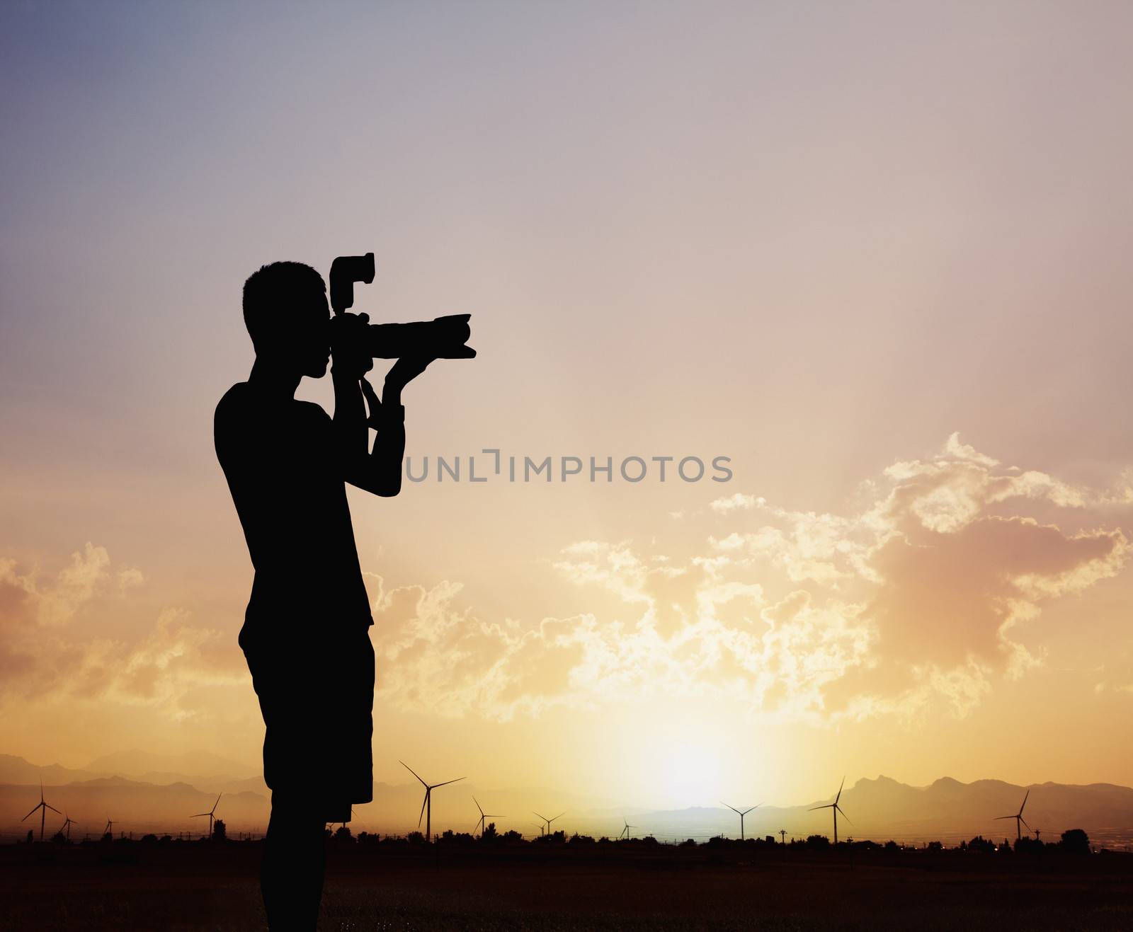 Silhouette of man taking photos with his camera at sunset with a dramatic sky by XiXinXing