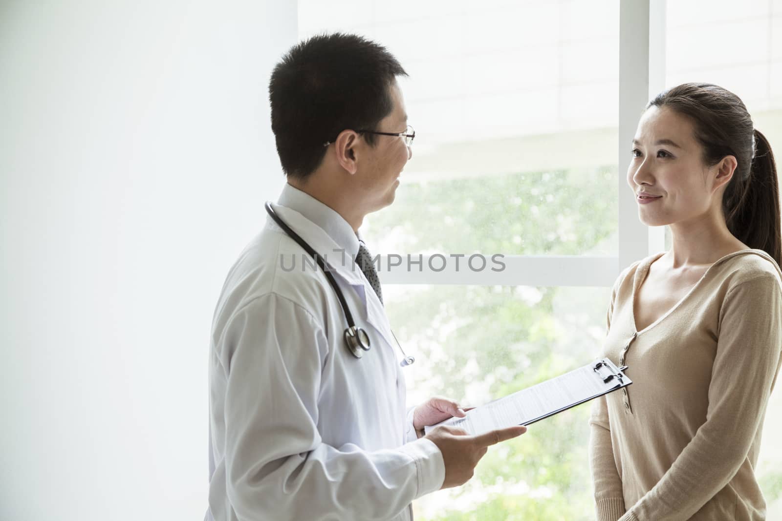 Doctor holding medical charts and discussing with a female patient in the hospital