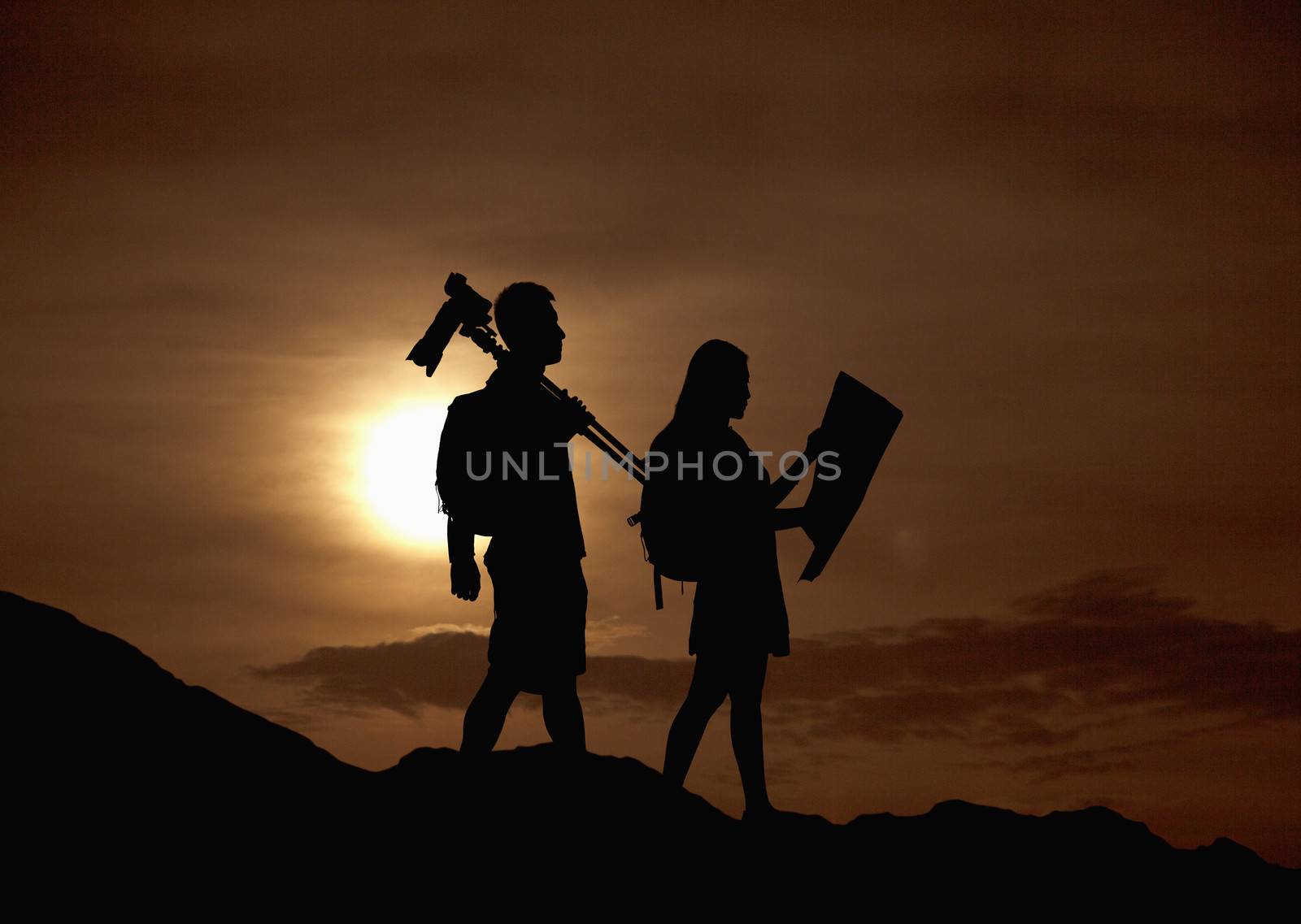 Silhouette of two people hiking and carrying camera and a map in nature at sunset by XiXinXing