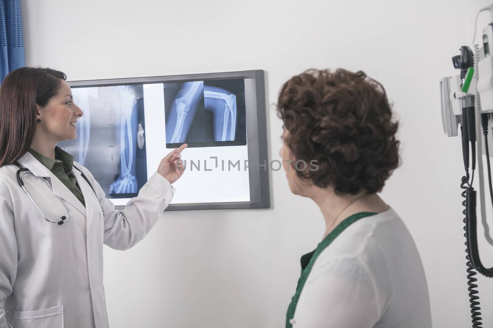 Young female doctor pointing to an x-ray with a patient sitting down 