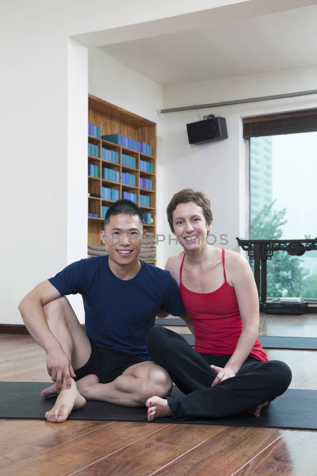 Two people relaxing and looking at camera in a yoga studio by XiXinXing