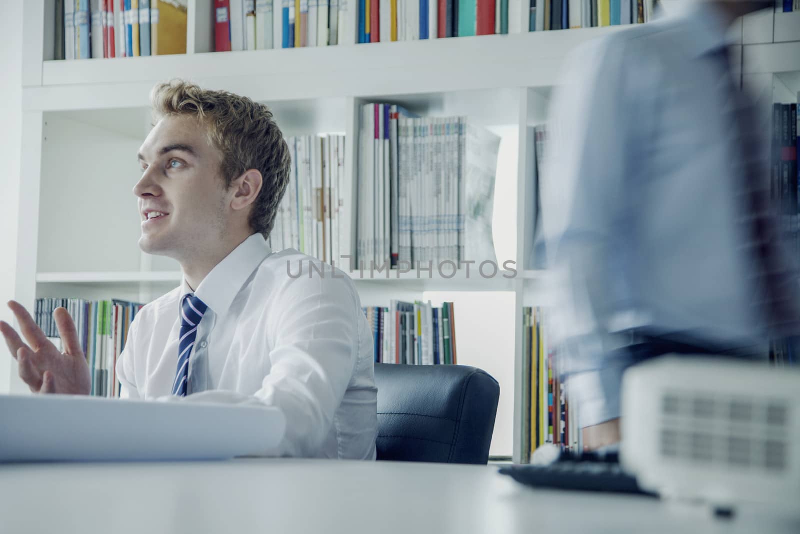 Young businessman discussing at a business meeting with colleague behind him