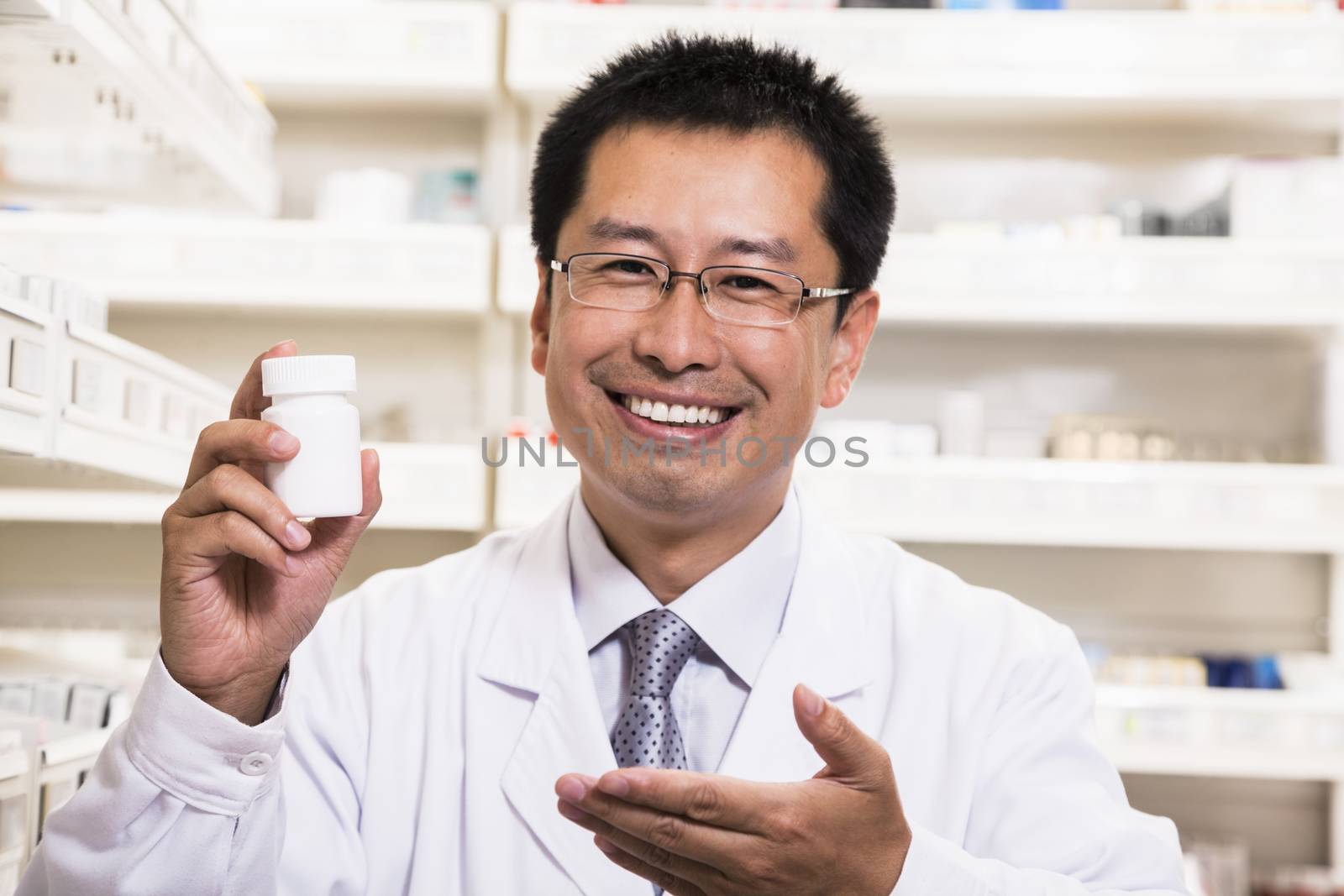 Portrait of smiling pharmacist holding a prescription medication bottle in his hand by XiXinXing