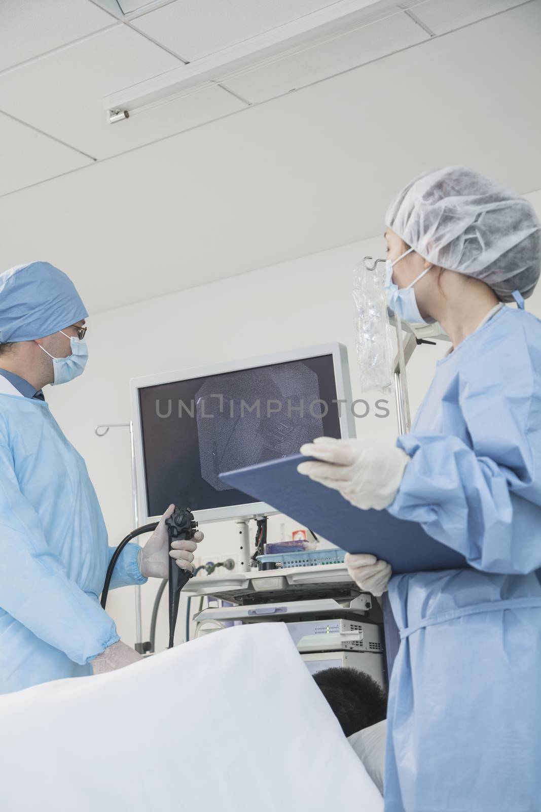 Two surgeons preparing for surgery, patient lying down