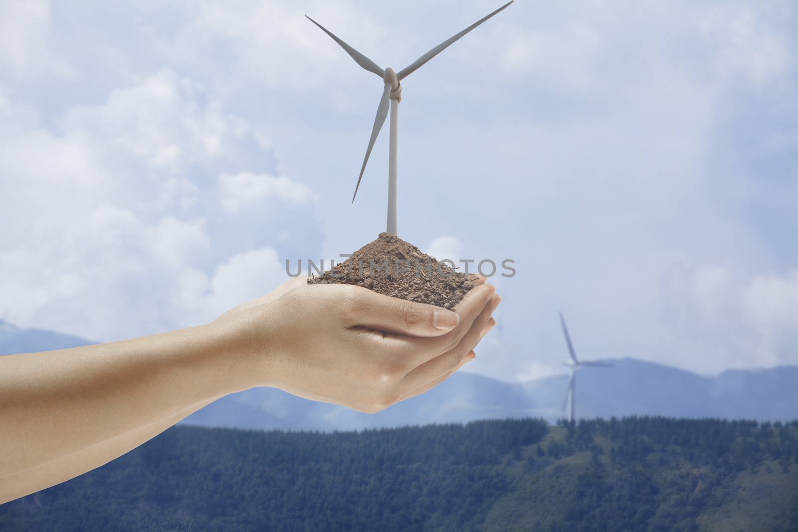 Hands holding soil with a wind turbine growing out from the middle